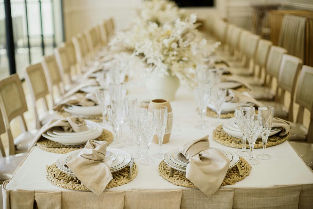 Chic wedding reception table setup featuring neutral tones, crystal glassware, and floral centerpiece.